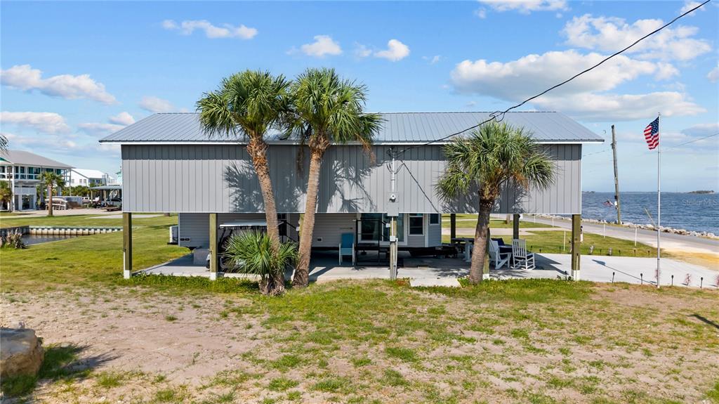 An elevated house with a metal roof stands on stilts near a body of water — 758 MAIN STREET, HORSESHOE BEACH, FL