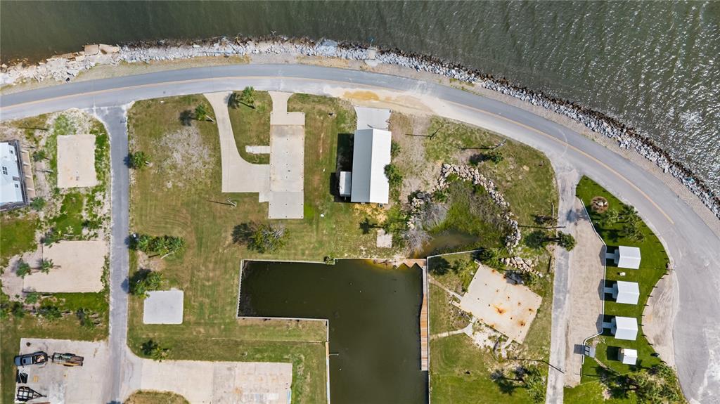 An aerial view shows a waterfront property with a small building, concrete pads, and docks — 758 MAIN STREET, HORSESHOE BEACH, FL