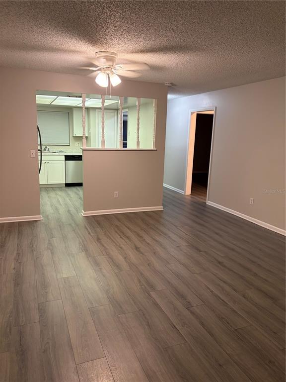 A living room with wood-look flooring leads to a kitchen with a partial wall divider — 7081 BALBOA DRIVE UNIT 7081, ORLANDO, FL