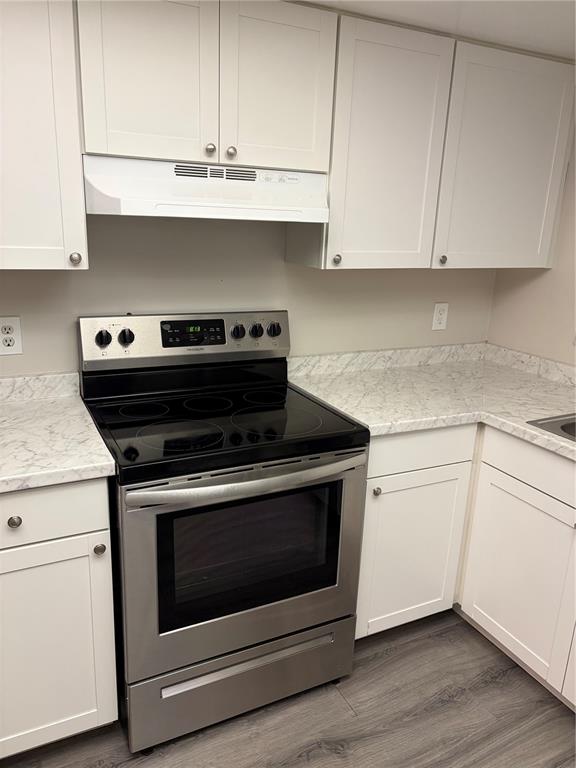 A kitchen features white cabinets, a stainless steel electric range, and marble-patterned countertops — 7081 BALBOA DRIVE UNIT 7081, ORLANDO, FL