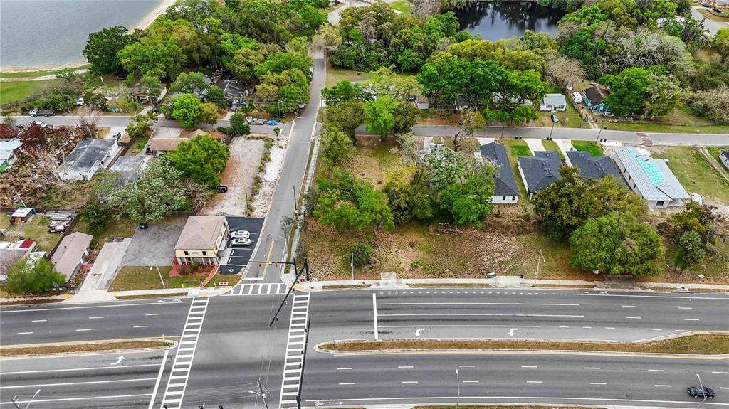 An aerial view shows a vacant lot situated between a multi-lane road and residential houses — 105 N KIRKMAN RD, ORLANDO, FL