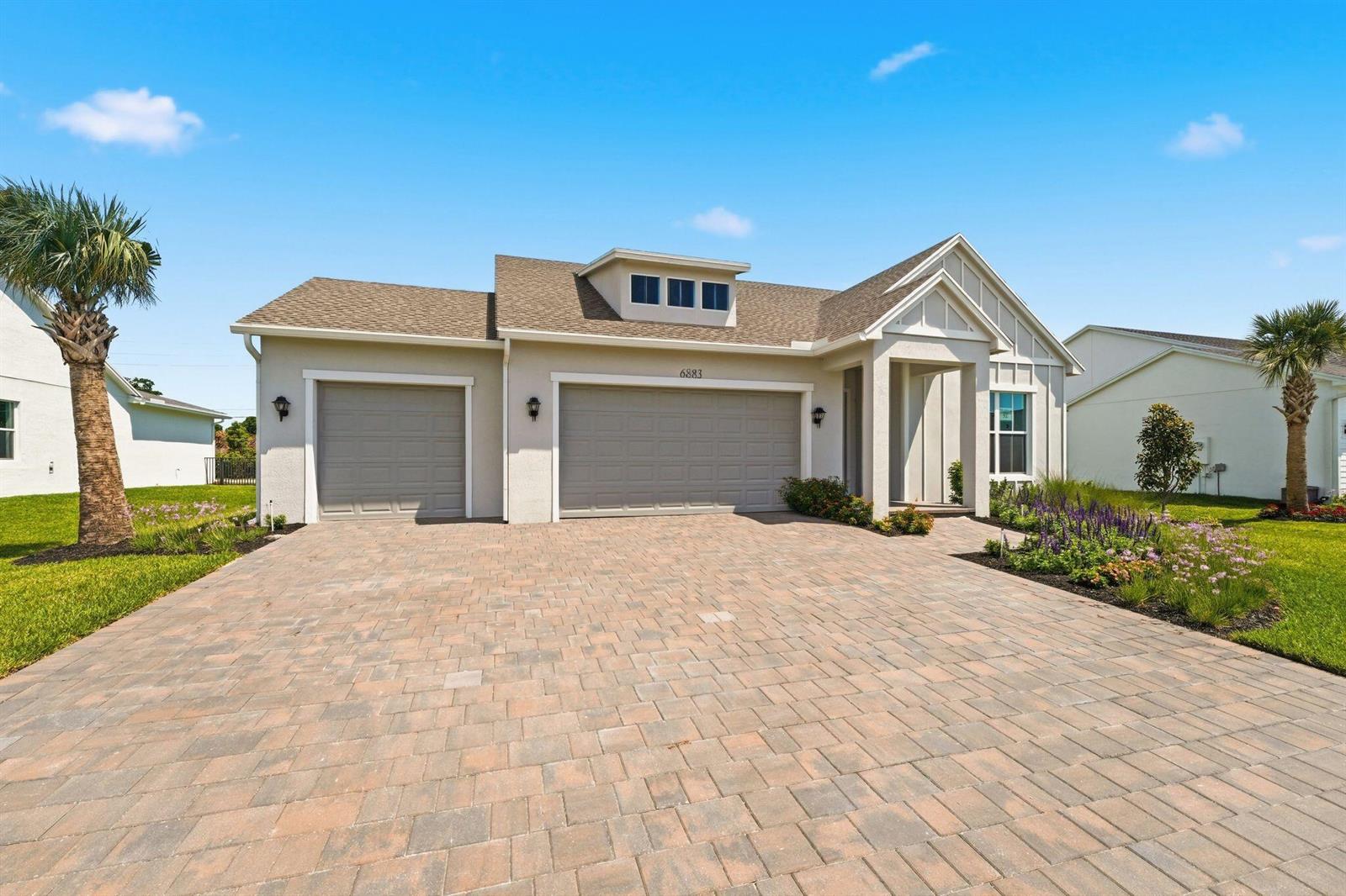 A single-story house with a three-car garage and a paved driveway under a blue sky — 6883 68th Square, Vero Beach FL 32967, VERO BEACH, FL