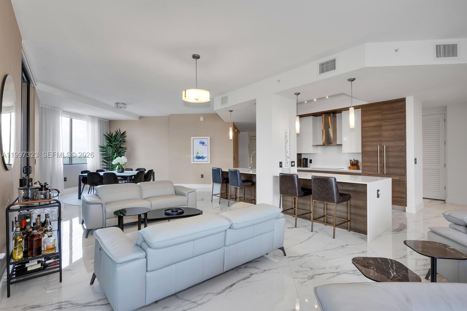 An open-concept living and dining area features white marble floors, modern furniture, and a kitchen — 301 Altara Ave, Coral Gables FL 33146, CORAL GABLES, FL