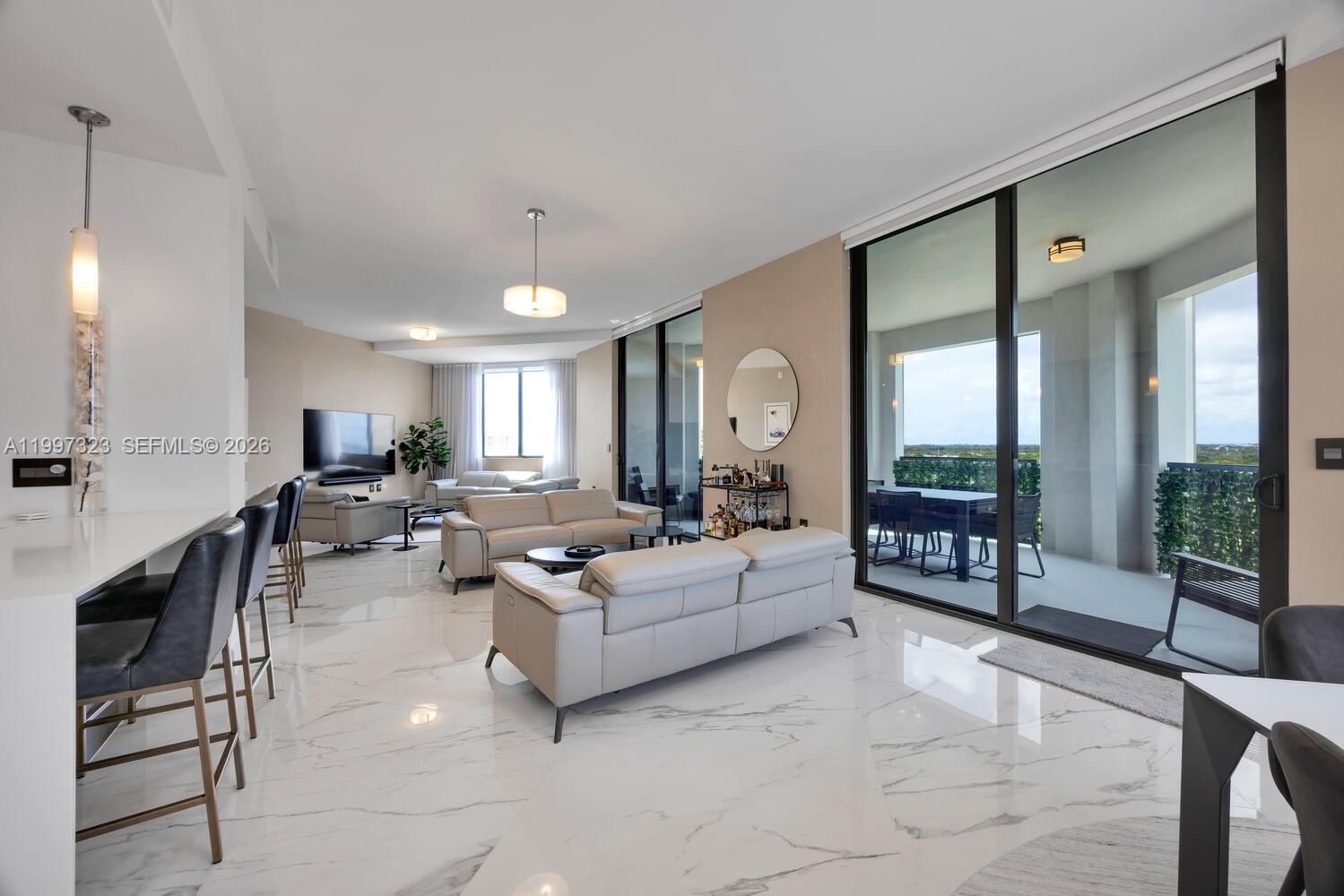 A modern living room features white marble floors, light-colored leather sofas, and a large balcony — 301 Altara Ave, Coral Gables FL 33146, CORAL GABLES, FL