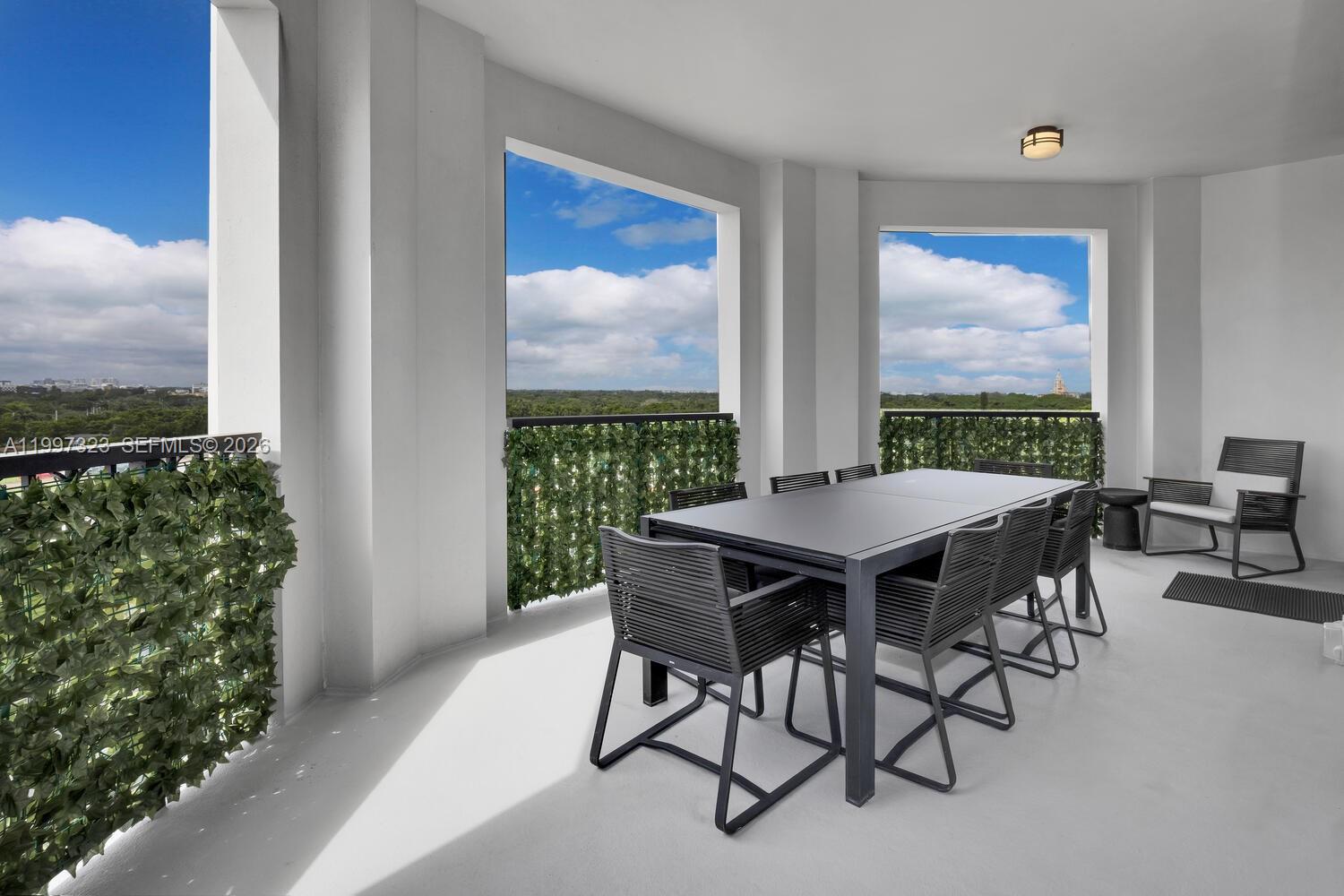 A covered balcony features a dining table with chairs and artificial greenery along the railing — 301 Altara Ave, Coral Gables FL 33146, CORAL GABLES, FL