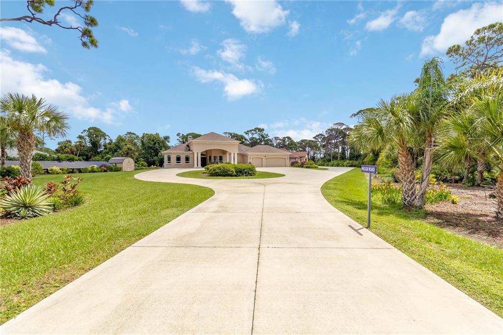 A long concrete driveway leads to a single-story house with a circular island and landscaping — 1991 HEASLEY ROAD, ENGLEWOOD, FL