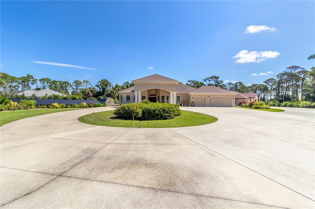 A large house with a circular driveway and a central landscaped island under a blue sky — 1991 HEASLEY ROAD, ENGLEWOOD, FL