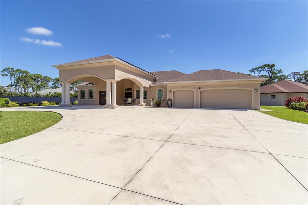 A beige house with a large concrete driveway, a covered entryway, and a three-car garage — 1991 HEASLEY ROAD, ENGLEWOOD, FL