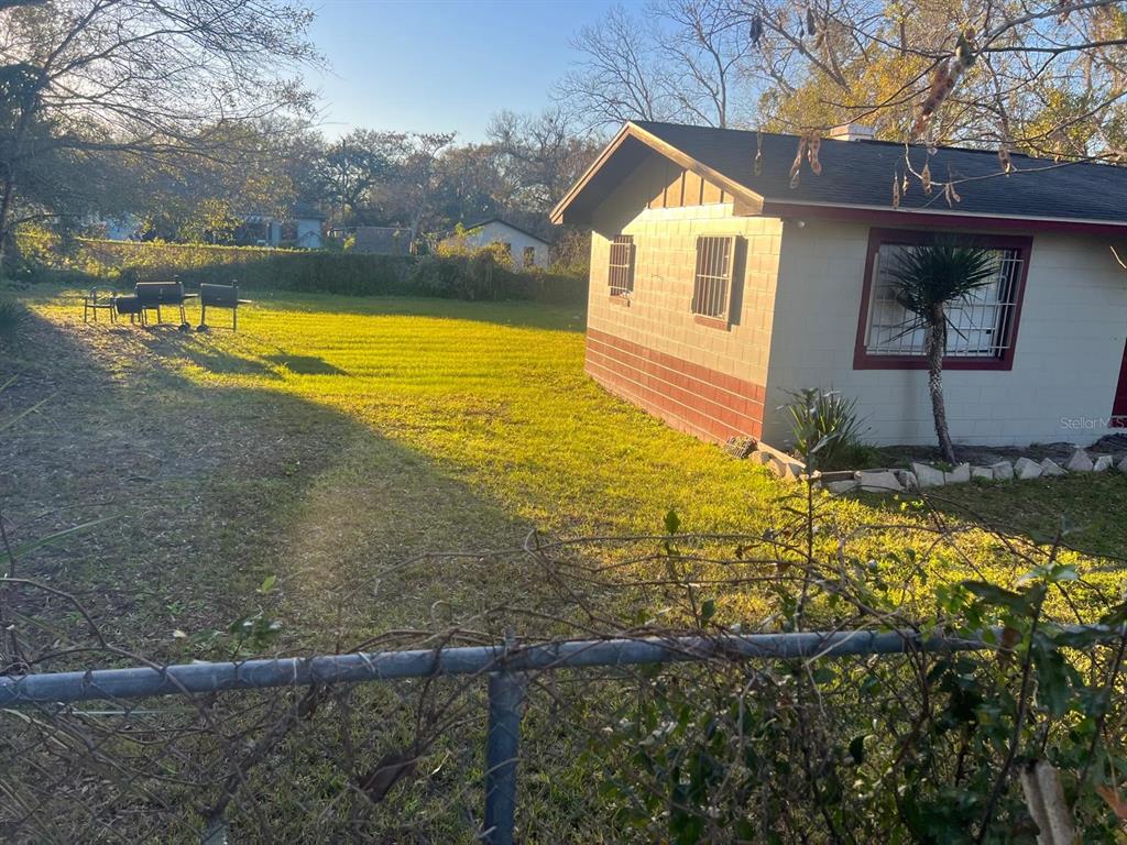 A side view of a house with concrete block walls and a large grassy yard — 1112/1114 S BAY AVENUE, SANFORD, FL