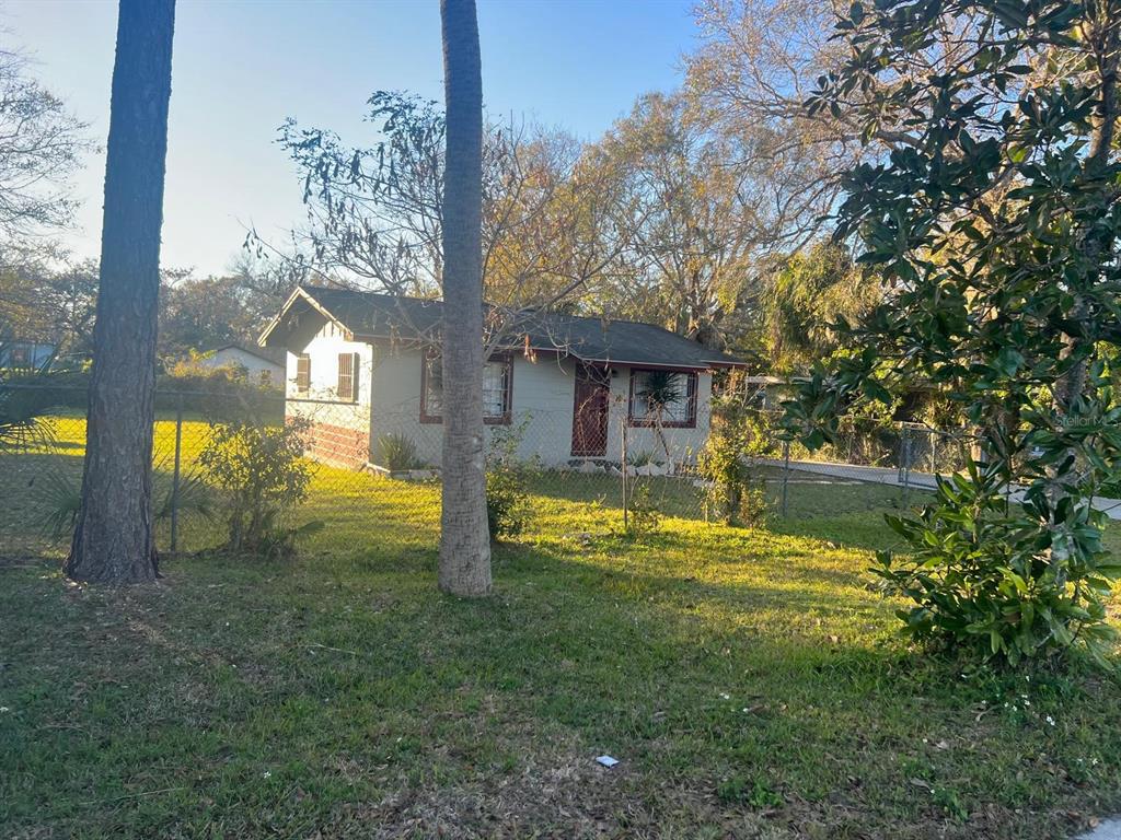 A single-story house with light siding and a dark roof sits behind a chain-link fence — 1112/1114 S BAY AVENUE, SANFORD, FL