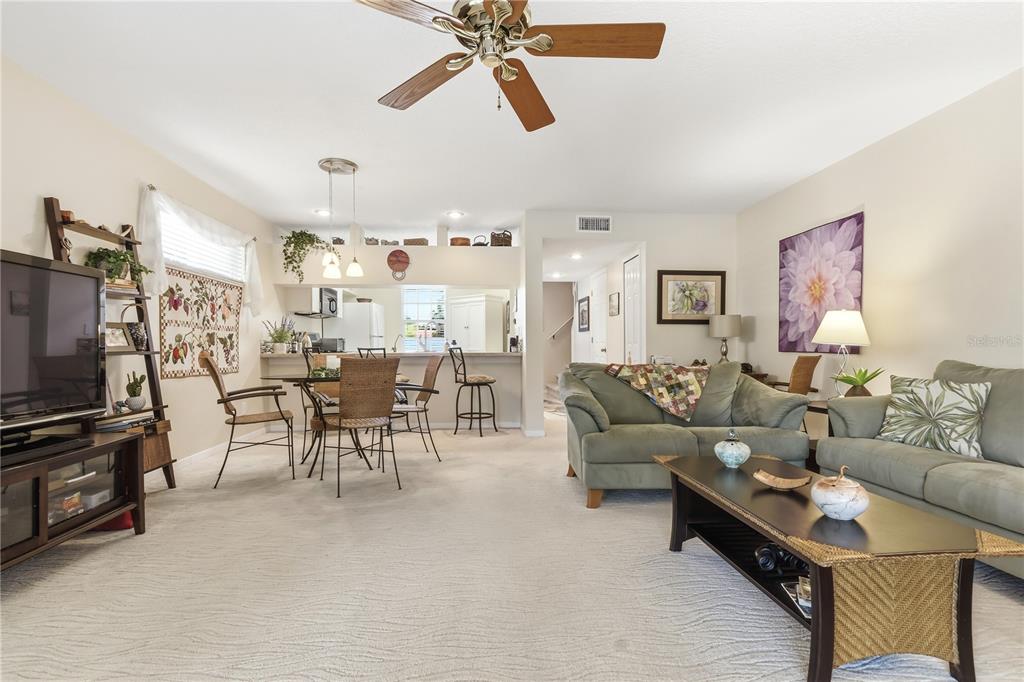 A living room and dining area feature carpeted floors, a ceiling fan, and neutral walls — 9034 LAKE PLACE LANE UNIT 9034, TAMPA, FL