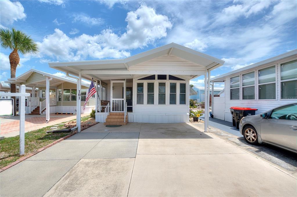 A white manufactured home with a covered carport and a front porch under a blue sky — 42769 HIGHWAY 27 UNIT 101, DAVENPORT, FL