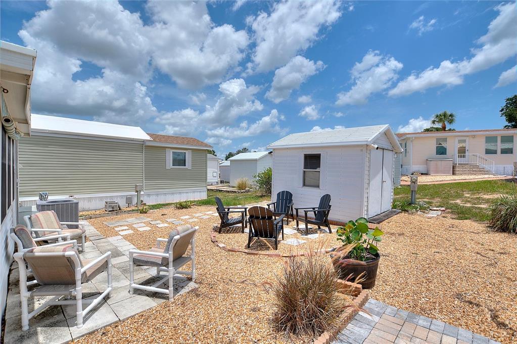 An outdoor patio area features gravel, stone pavers, a small shed, and several chairs — 42769 HIGHWAY 27 UNIT 101, DAVENPORT, FL