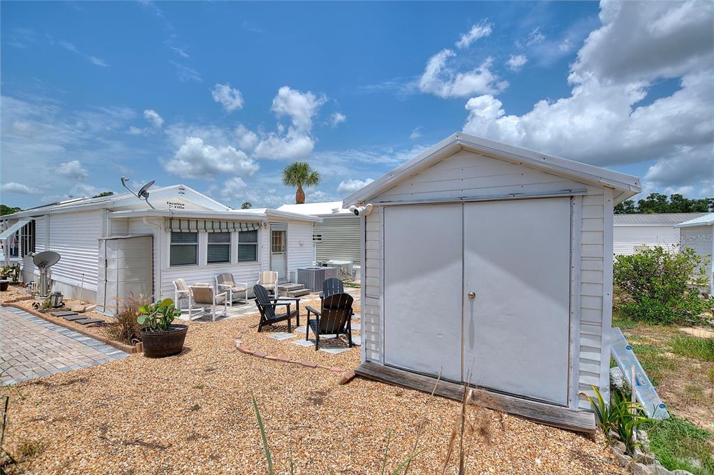 A white storage shed sits on a gravel patio beside a mobile home — 42769 HIGHWAY 27 UNIT 101, DAVENPORT, FL