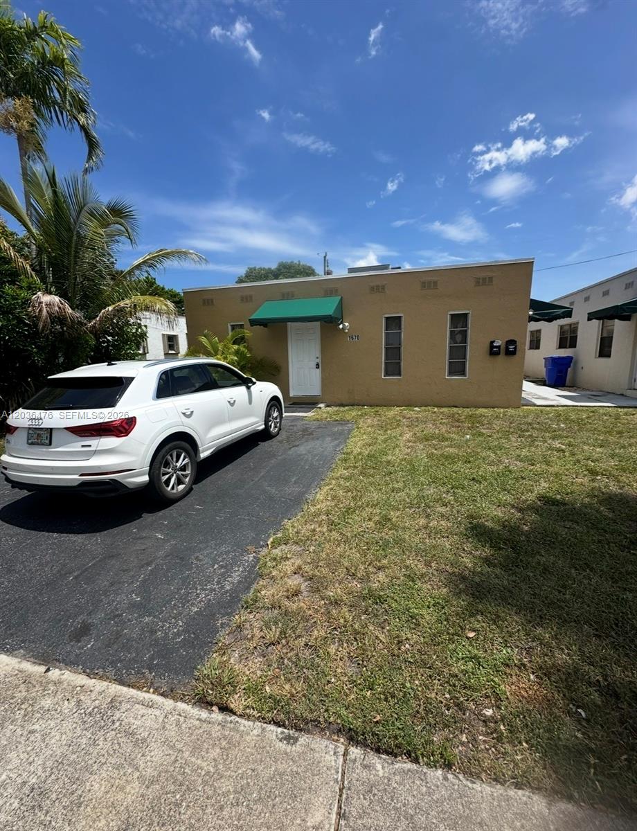 A white SUV is parked on a driveway in front of a tan, single-story building — 1670 Harding St # A, Hollywood FL 33020, HOLLYWOOD, FL