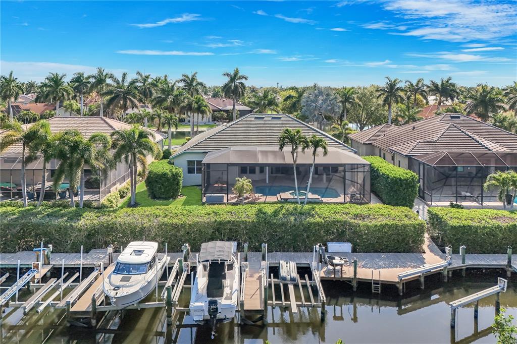 An aerial view of a waterfront house with a pool, screened lanai, and private boat docks — 15930 CATALPA COVE DRIVE, FORT MYERS, FL