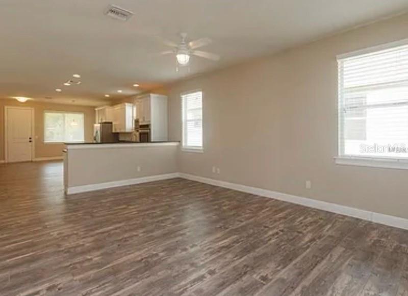 An open-concept living area features wood-look flooring, a ceiling fan, and a kitchen breakfast bar — 0 FISHER LANE WAY, OCKLAWAHA, FL