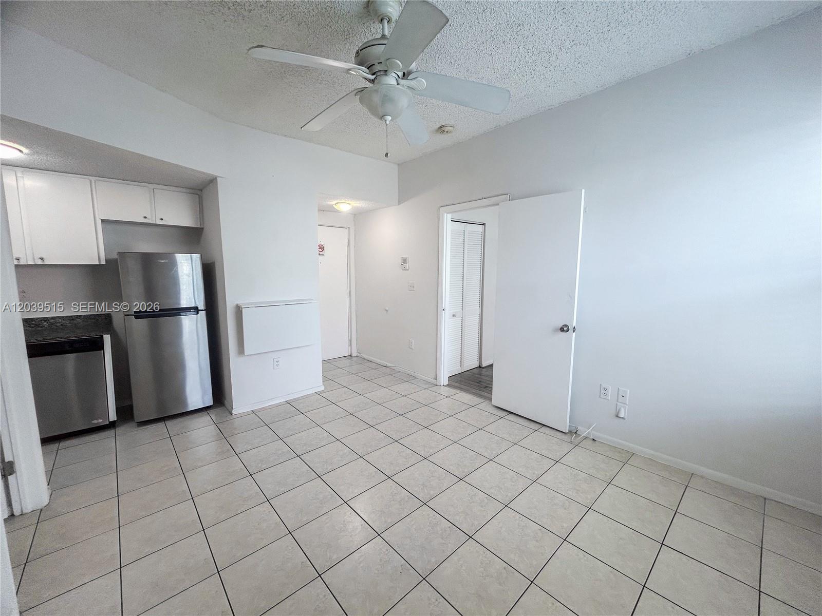 A kitchen area features white cabinets, stainless steel appliances, and light-colored tile flooring — 1218 Drexel Ave # 204, Miami Beach FL 33139, MIAMI BEACH, FL