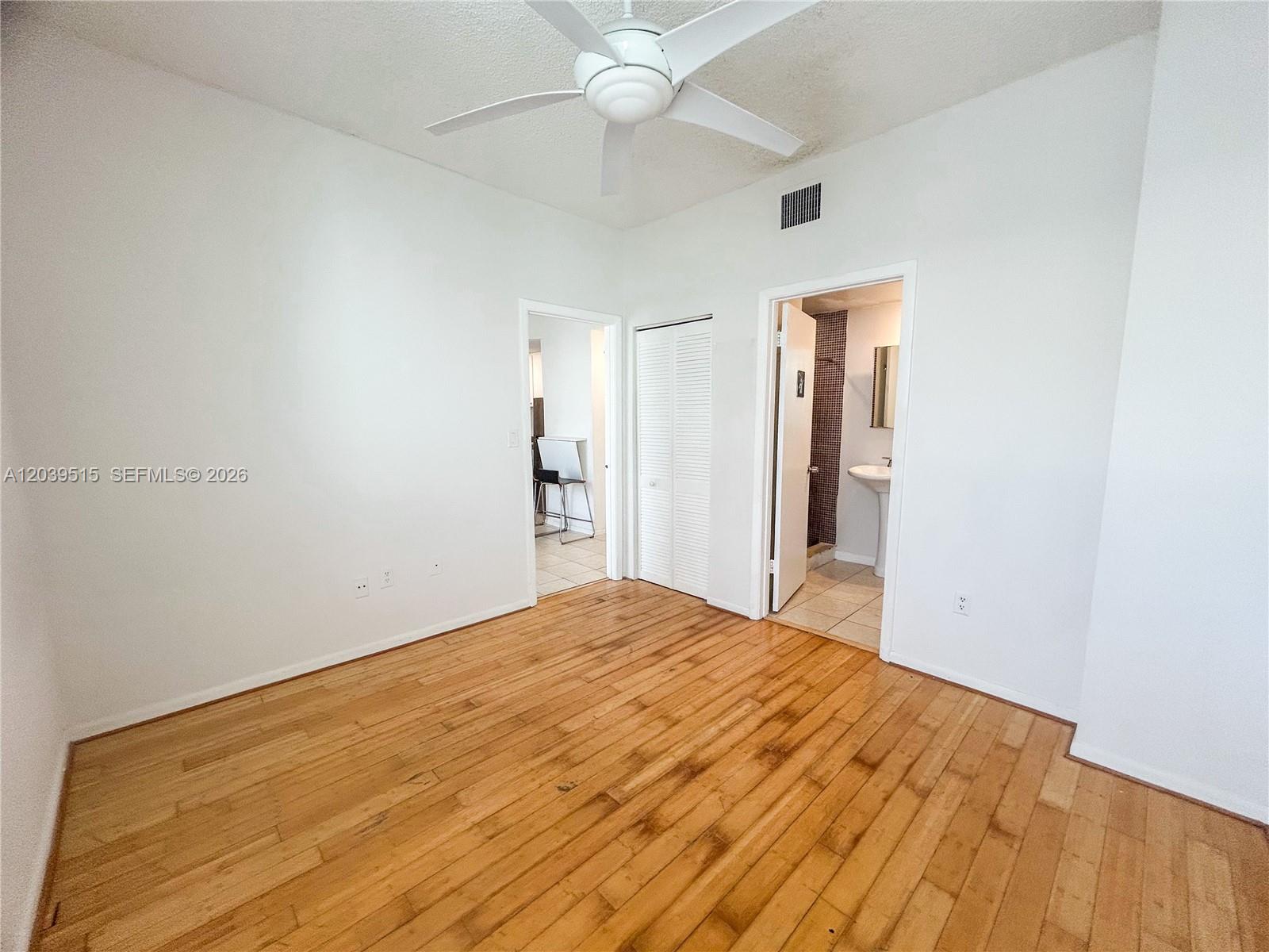 This bedroom features white walls, a ceiling fan, wood flooring, and two doorways — 1218 Drexel Ave # 204, Miami Beach FL 33139, MIAMI BEACH, FL