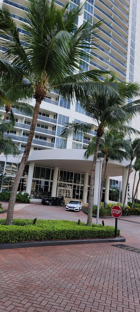 The exterior of a high-rise building features a covered entrance with palm trees and cars — 1850 S Ocean Dr # 3007, Hallandale Beach FL 33009, HALLANDALE BEACH, FL
