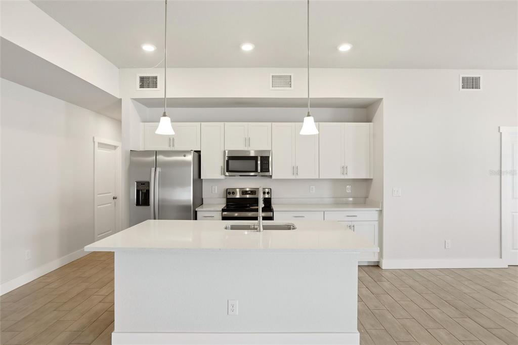 A modern kitchen features white cabinets, stainless steel appliances, and a central island with a sink — 870 COLUMBIA STREET, PORT CHARLOTTE, FL