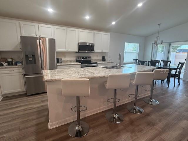 A modern kitchen features white cabinets, stainless steel appliances, and a granite-topped island with stools — 4363 SWAN STREET, HAINES CITY, FL