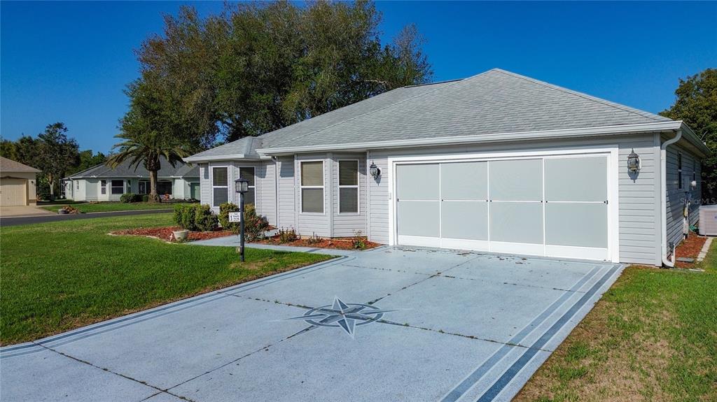 A light gray single-story house with a painted driveway featuring a compass rose design — 2129 ZARAGOZA PLACE, THE VILLAGES, FL