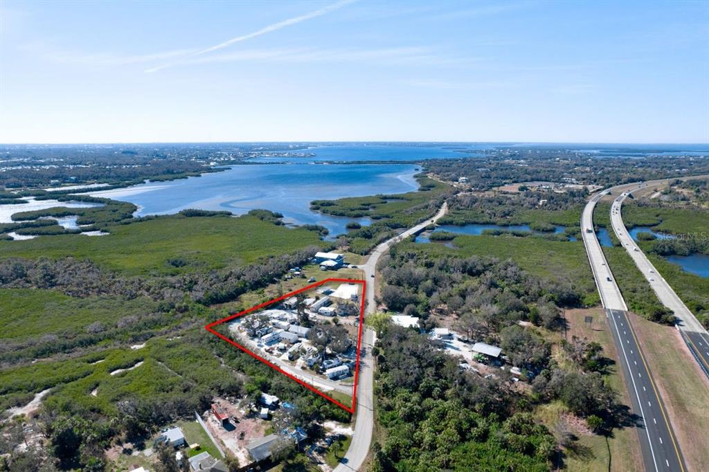An aerial view shows a triangular property containing multiple mobile homes near a highway — 515 77TH STREET E UNIT 10, PALMETTO, FL