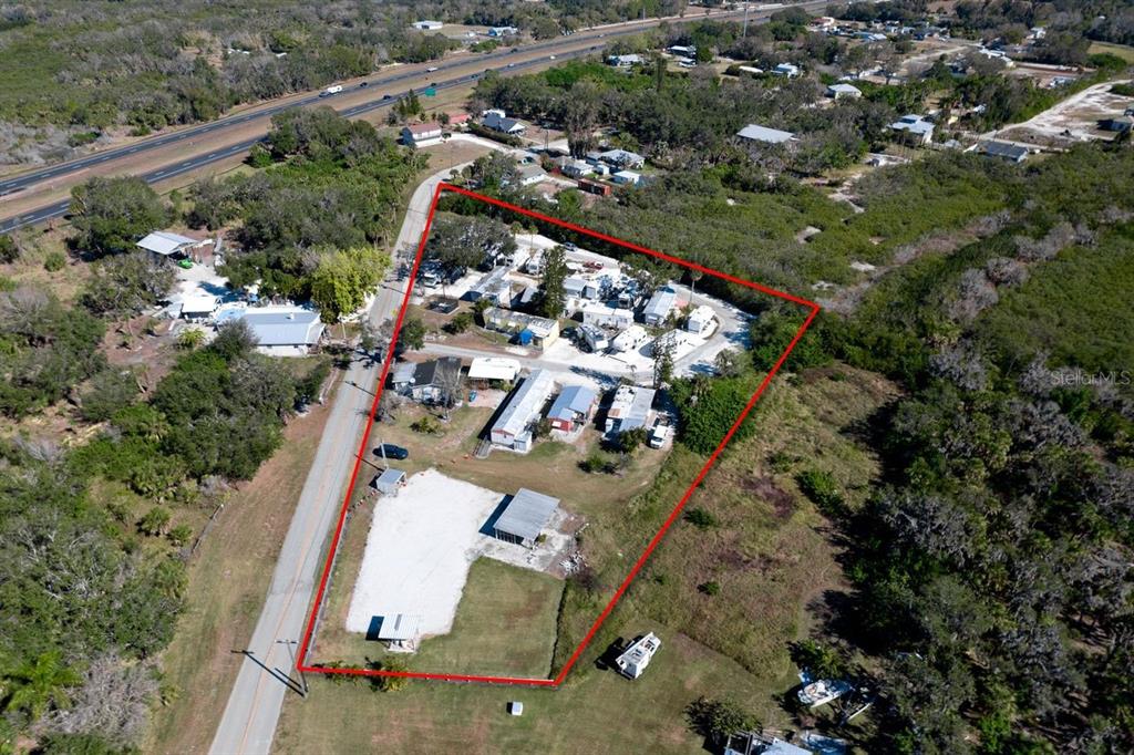 An aerial view shows a fenced property with multiple mobile homes and outbuildings near a highway — 515 77TH STREET E UNIT 10, PALMETTO, FL