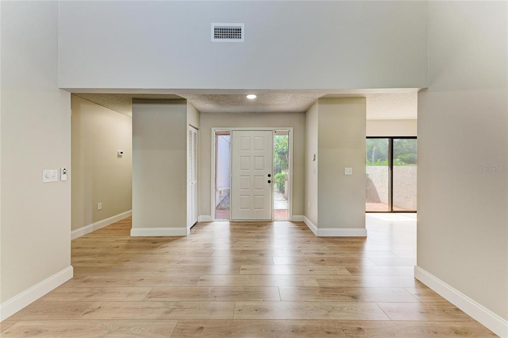 An entryway with light wood-look flooring, a white front door, and high ceilings — 4515 WINSTON LANE N UNIT 47, SARASOTA, FL