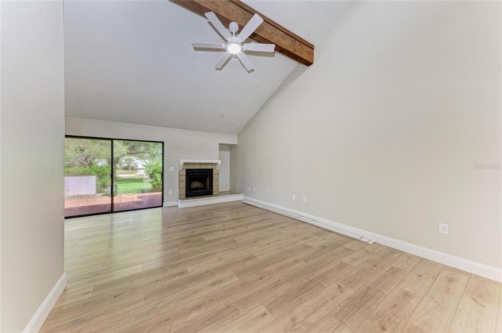 A living room with wood-look flooring, a vaulted ceiling, a ceiling fan, and a fireplace — 4515 WINSTON LANE N UNIT 47, SARASOTA, FL