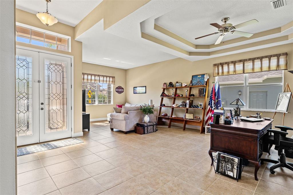 A spacious room with tile flooring, a tray ceiling, a desk, and a seating area — 3303 STONEGATE FALLS DRIVE, LAND O LAKES, FL