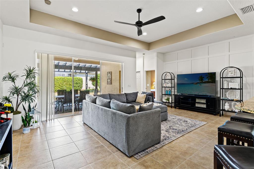 A living room features a grey sectional sofa, a television, and sliding doors to a patio — 3303 STONEGATE FALLS DRIVE, LAND O LAKES, FL