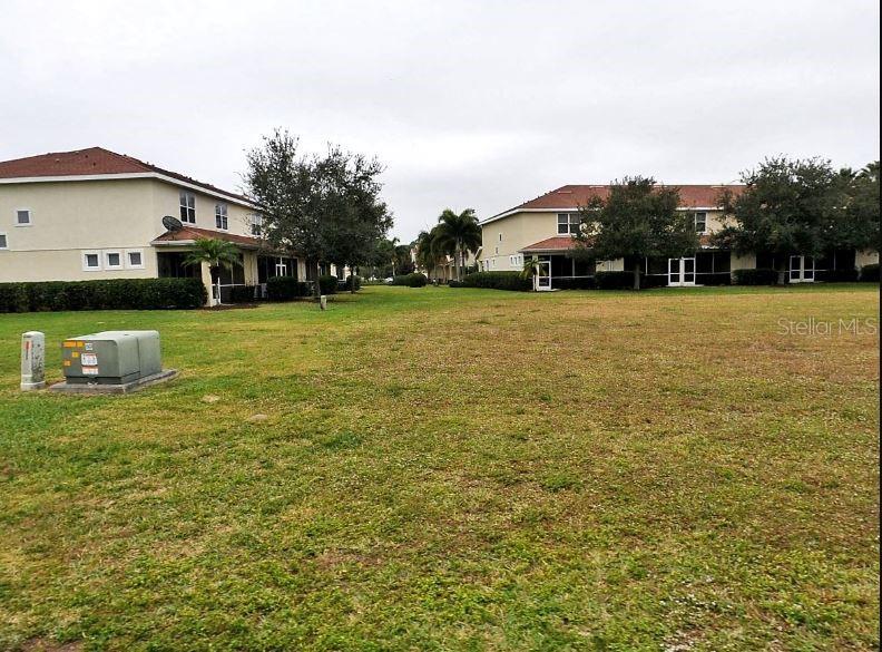 A grassy lawn sits between two multi-story residential buildings under a cloudy sky — JONAH DRIVE, NORTH PORT, FL