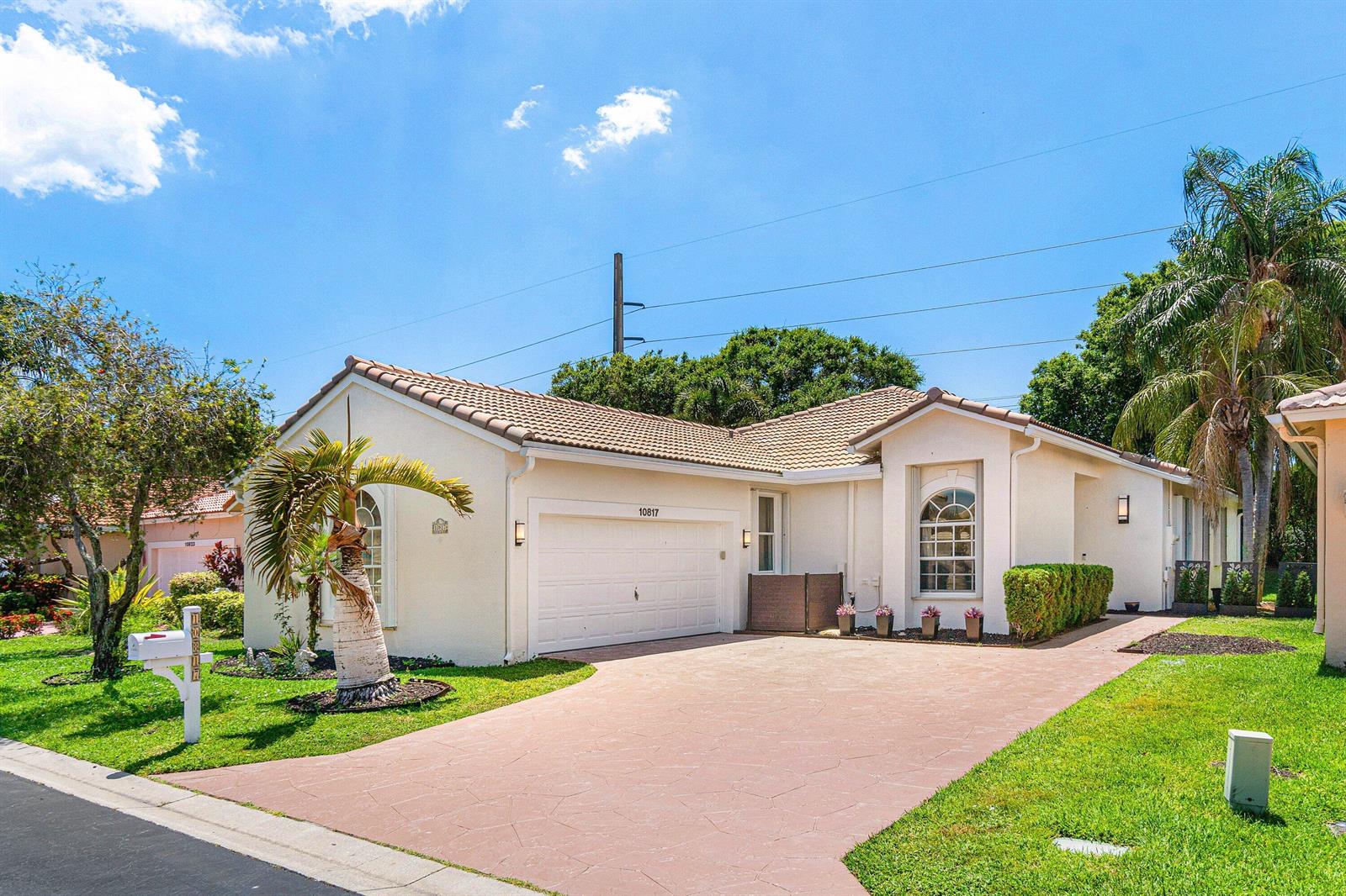 A single-story house with a beige stucco exterior, a tile roof, and a paved driveway — 10817 Fillmore Drive, Boynton Beach FL 33437, BOYNTON BEACH, FL