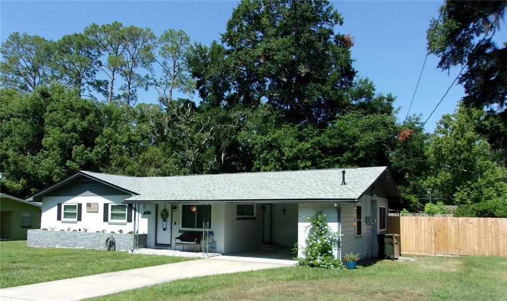 A single-story white house with a gray roof, a carport, and a brick planter box — 428 NE 21ST TERRACE, OCALA, FL