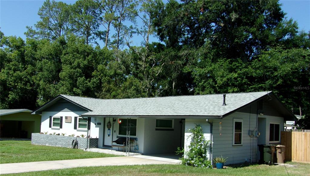 A single-story house with a gray shingled roof, white siding, and an attached carport — 428 NE 21ST TERRACE, OCALA, FL