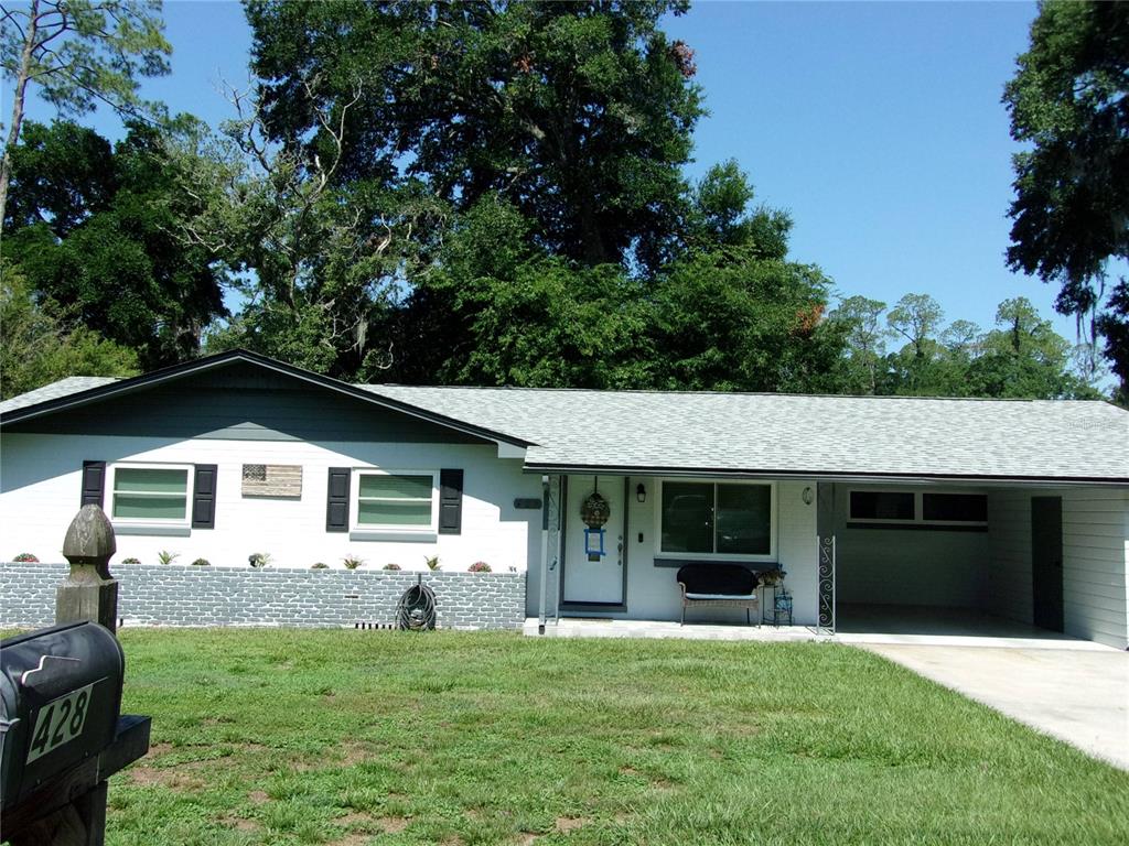 A single-story house with white siding, a gray stone base, and an attached carport — 428 NE 21ST TERRACE, OCALA, FL
