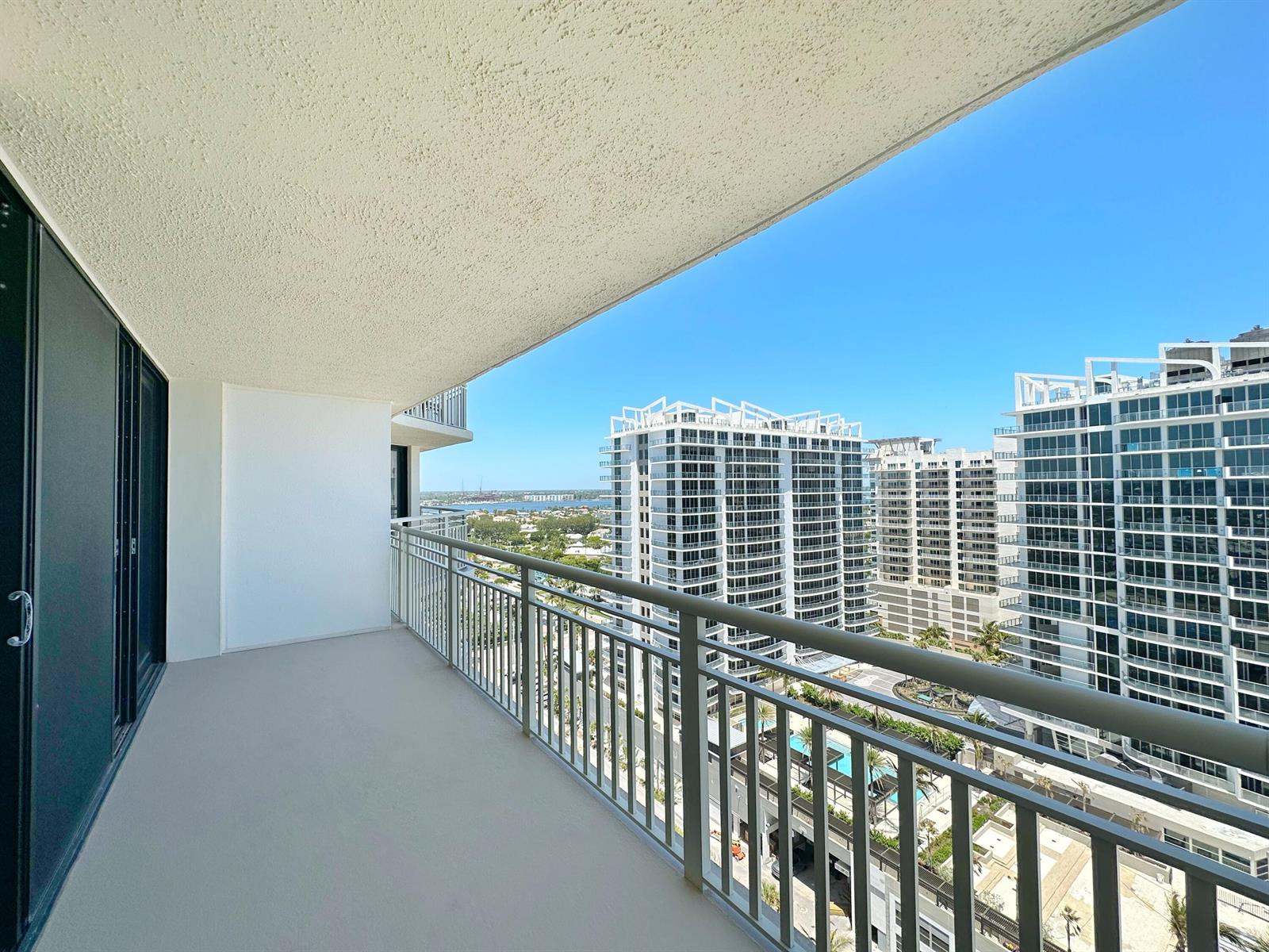 A high-rise balcony with a metal railing overlooks neighboring apartment buildings and a distant waterway — 3000 N Ocean Drive # B, Singer Island FL 33404, SINGER ISLAND, FL