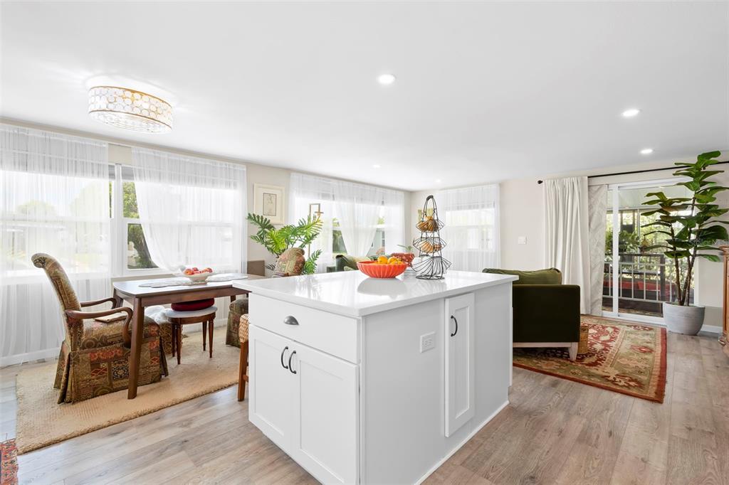 A kitchen island with a white countertop sits in an open-concept living and dining area — 7165 MOUNT GEORGETOWN DRIVE NE UNIT 571, ST PETERSBURG, FL
