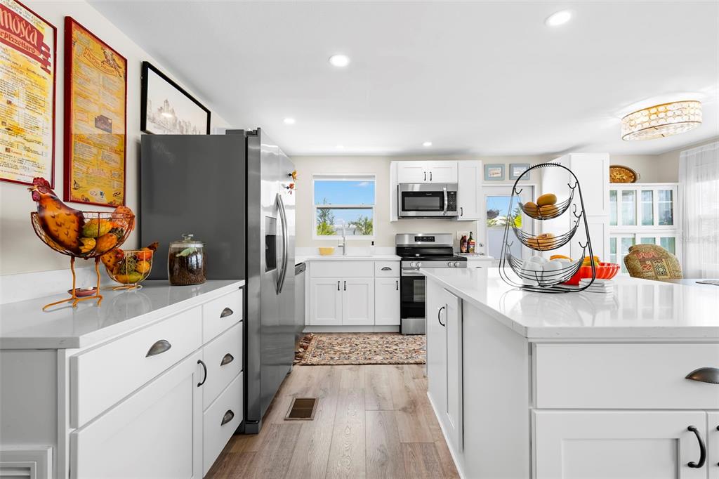 A bright kitchen features white cabinets, stainless steel appliances, and a large central island — 7165 MOUNT GEORGETOWN DRIVE NE UNIT 571, ST PETERSBURG, FL
