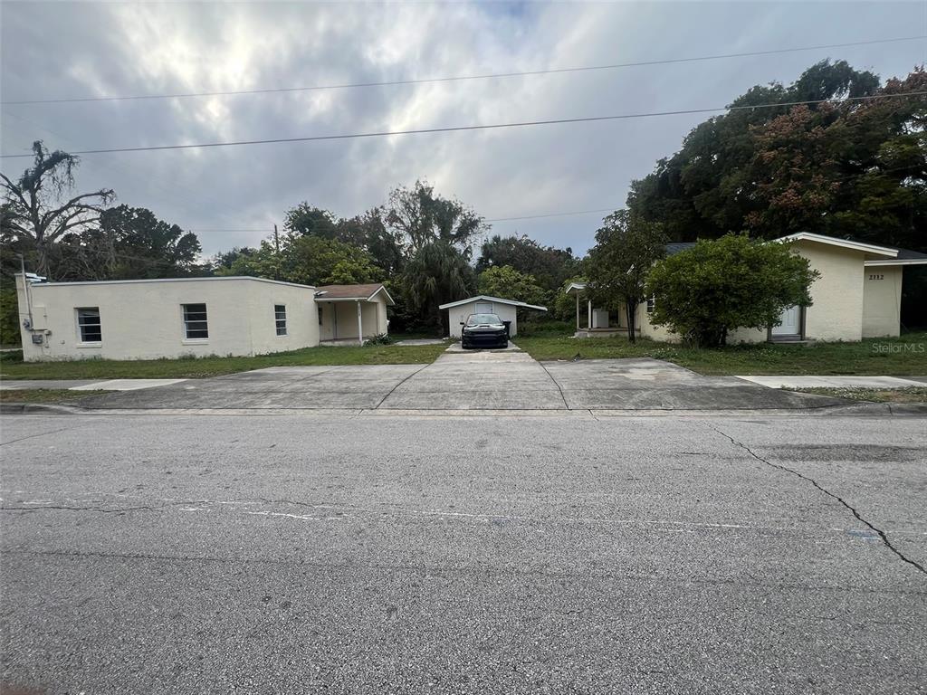 A street view of two single-story residential buildings with a shared concrete driveway and carport — 2112 LEE STREET, ORLANDO, FL