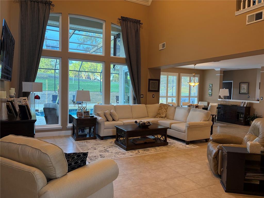 A spacious living room features a large sectional sofa, high ceilings, and floor-to-ceiling windows — 889 EAGLE CLAW COURT, LAKE MARY, FL