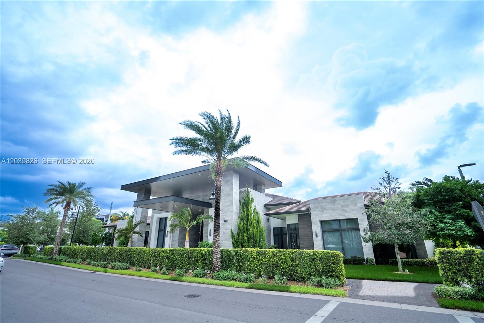 A modern, single-story stone house features a prominent porte-cochère and a manicured hedge-lined front yard — 4740 NW 84th Ct # 32, Doral FL 33166, DORAL, FL