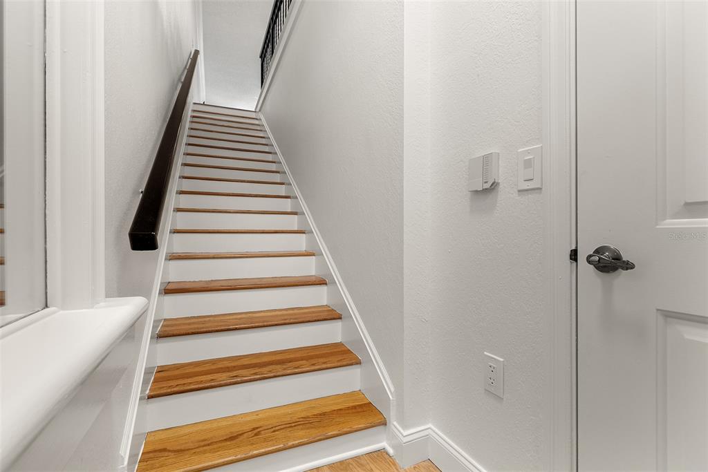 A staircase with wooden treads and white risers leads to an upper floor — 910 NORMANDY TRACE ROAD, TAMPA, FL