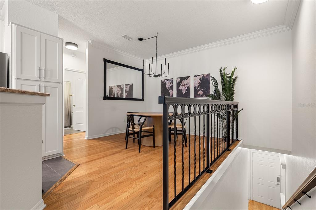 A dining area features hardwood floors, a black metal railing, and a modern chandelier — 910 NORMANDY TRACE ROAD, TAMPA, FL