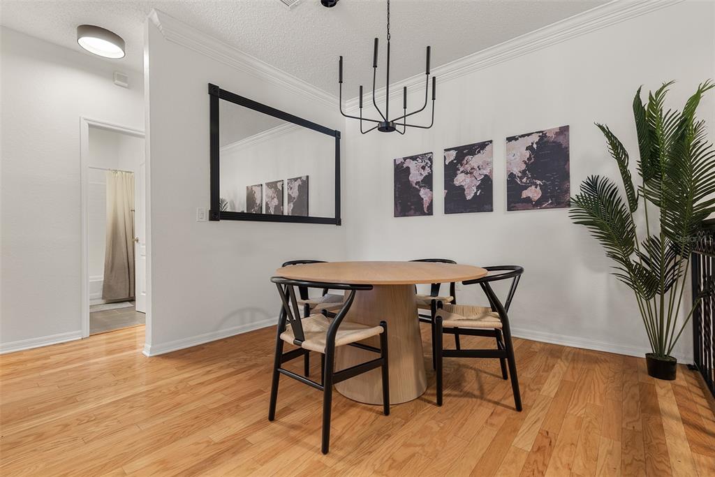 A dining area features a round wooden table, black chairs, a chandelier, and wall art — 910 NORMANDY TRACE ROAD, TAMPA, FL