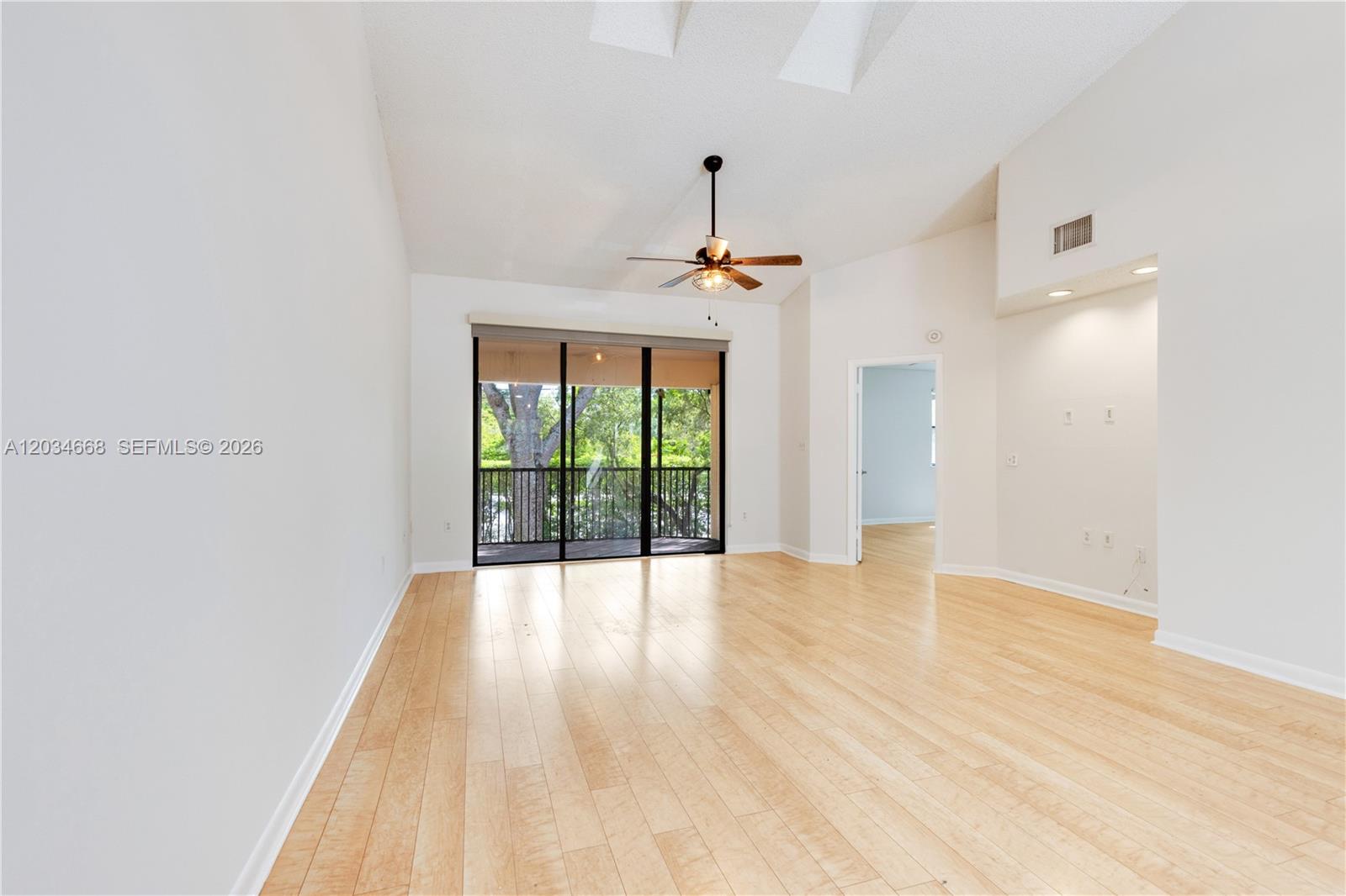 An empty living room features light wood flooring, a ceiling fan, and a sliding glass door — 104 NW 98th Ter # 104, Plantation FL 33324, PLANTATION, FL