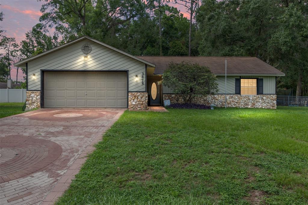 A single-story house with a stone-accented facade, green siding, and a circular brick driveway — 3475 NE 43RD PLACE, OCALA, FL