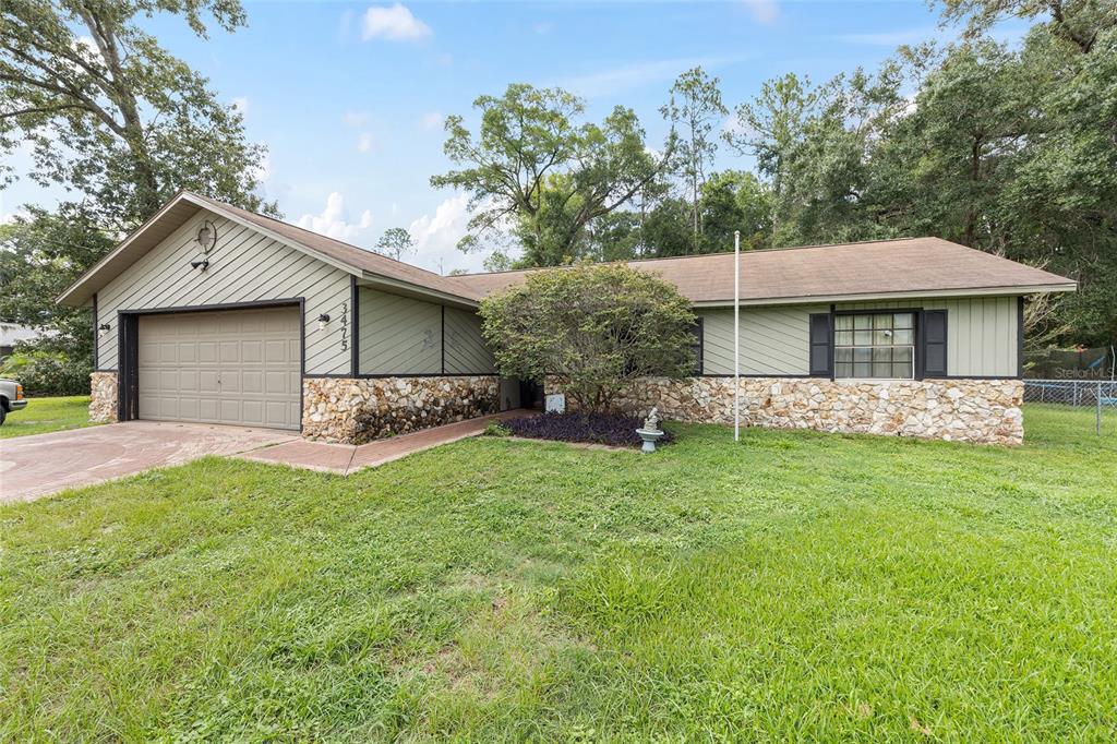 A single-story house with a stone facade, green siding, and an attached two-car garage — 3475 NE 43RD PLACE, OCALA, FL